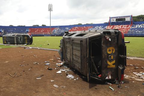 Bei Fußballkrawallen zerstörte Polizeiautos sind auf dem Spielfeld des Kanjuruhan-Stadions in Malang, Ostjava, Indonesien, zu sehen. © Trisnadi/AP/dpa