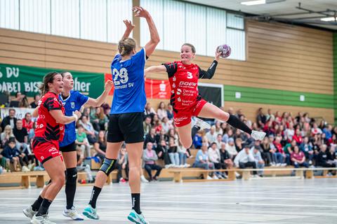 Amelie Berger steht in der Luft: Die in rot gekleidete Bundesliga-Handballerin siegt mit der HSG Bensheim/Auerbach deutlich gegen Liga-Konkurrent Buxtehuder SV mit 34:23.