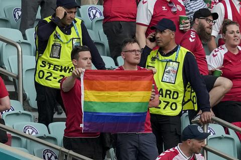 Vor dem Viertelfinale im Baku stehen Ordner neben zwei Dänemark-Fans, die eine Regenbogen-Fahne hochhalten.  Foto: dpa 