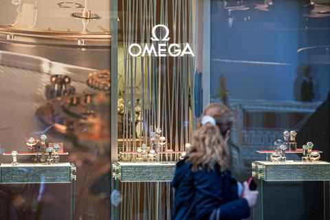 Eine Frau passiert eine Boutique des Schweizer Uhrenhersteller Omega. © Daniel Reinhardt/dpa