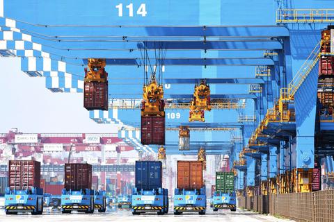 Portalkräne heben Container auf Transporter in einem Hafen in Qingdao in der ostchinesischen Provinz Shandong.